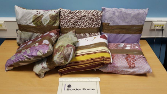 Seven patterned pillowcases sealed with brown packing tape, sitting on top of a wooden table.