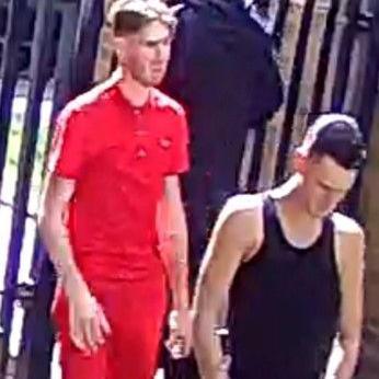 Two men walking - one man wearing a red shirt and shorts, the other wearing a blank tank top.