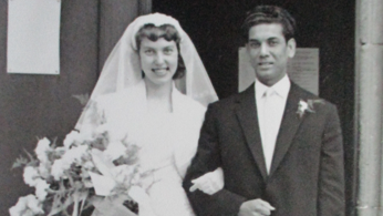 A married couple stand side by side in this black and white image.