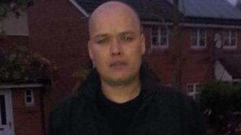 A head and shoulders picture of Kevin Bishop, who has a shaven head and is wearing a dark jacket and T-shirt.