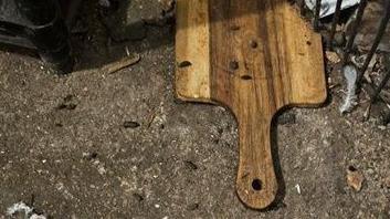 Rat droppings on top of a paddle used either for pizzas or as a chopping board. It is on the floor.