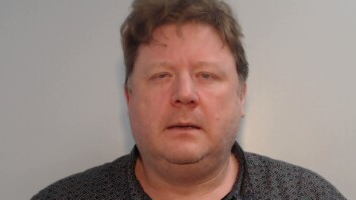 A mugshot of Nicholas Moxham show him staring directly at the camera. He is wearing a grey polo shirt.