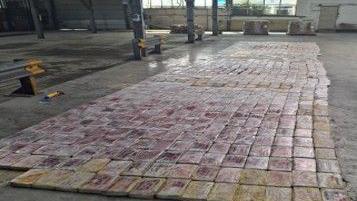 Plastic bags full of a white powder arranged in rows on the floor of a warehouse