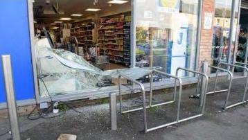 Front panel of glass smashed on Tesco express shop behind metal n- shape bike stands