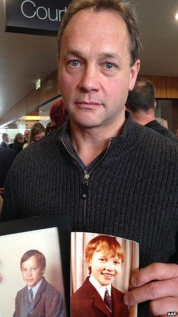 Peter Blenkiron holding photos of himself as a child