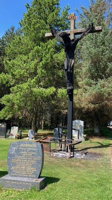 A large charred wooden crucifix, still upright in the cemetery