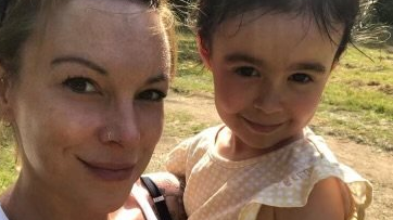 A smiling woman is holding her daughter up to the camera 