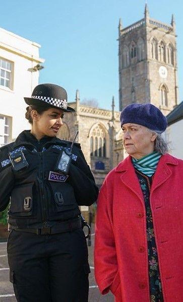 Actors Dawn French and Mandip Gill stand next to each other as they are filmed for BBC show Can You Keep a Secret? in Wells in Somerset. Gill is in a police uniform and French is wearing a red coat and a blue beret
