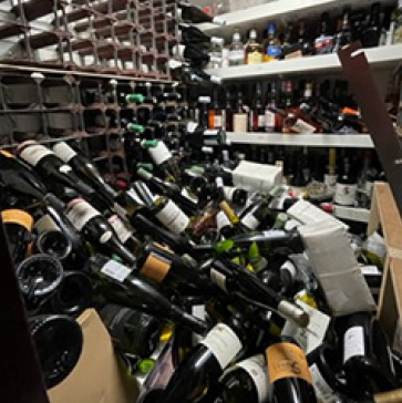 Wine bottles lying in a pile after falling from a large rack inside a railway coach