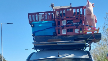 The roof of a car packed with a large box including a pink unicorn.