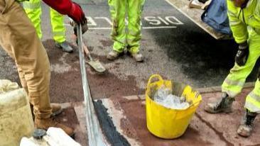 Workers putting in a cable tray into a pavement to allow on-street charging