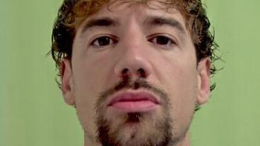 A police mugshot of Kane Jones, who has tousled dark hair, a goatee beard and brown eyes.