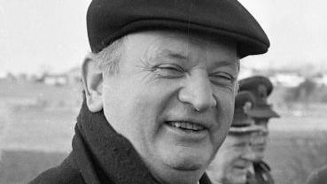 Eamonn Casey in a black and white photograph wearing a hat, smiling at the camera.