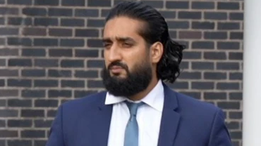 Abubakr Ben Yusaf, who wears a navy two piece suit, a blue tie and white shirt. He has brown long hair and a brown long haired beard. He is leaving Mold Crown Court and holds a blue folder under his left arm
