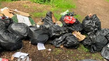 Black bin bags of rubbish lefts in a public path