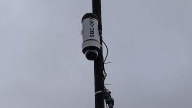 A image of a security camera device on a pole in the sky
