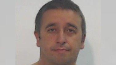 A police mugshot of a round-faced man with short brown hair