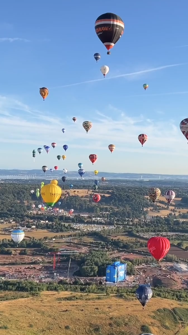 Lots of balloons hover over the landscape. 