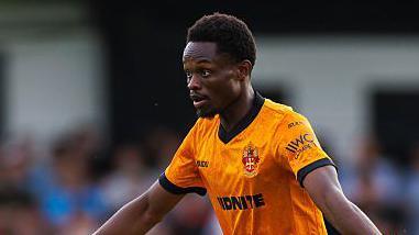 Rafiki Said in action for Wolves in pre-season. He is wearing the club's old gold shirt and shorts and has both arms stretched out.