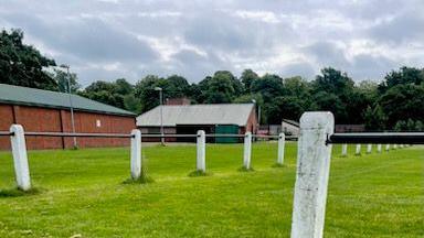 A field with concrete posts and a building in the background.