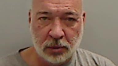 Mugshot of Hunt who is bald with a neat white beard and pitted complexion. The picture is blurry and very close up. 
