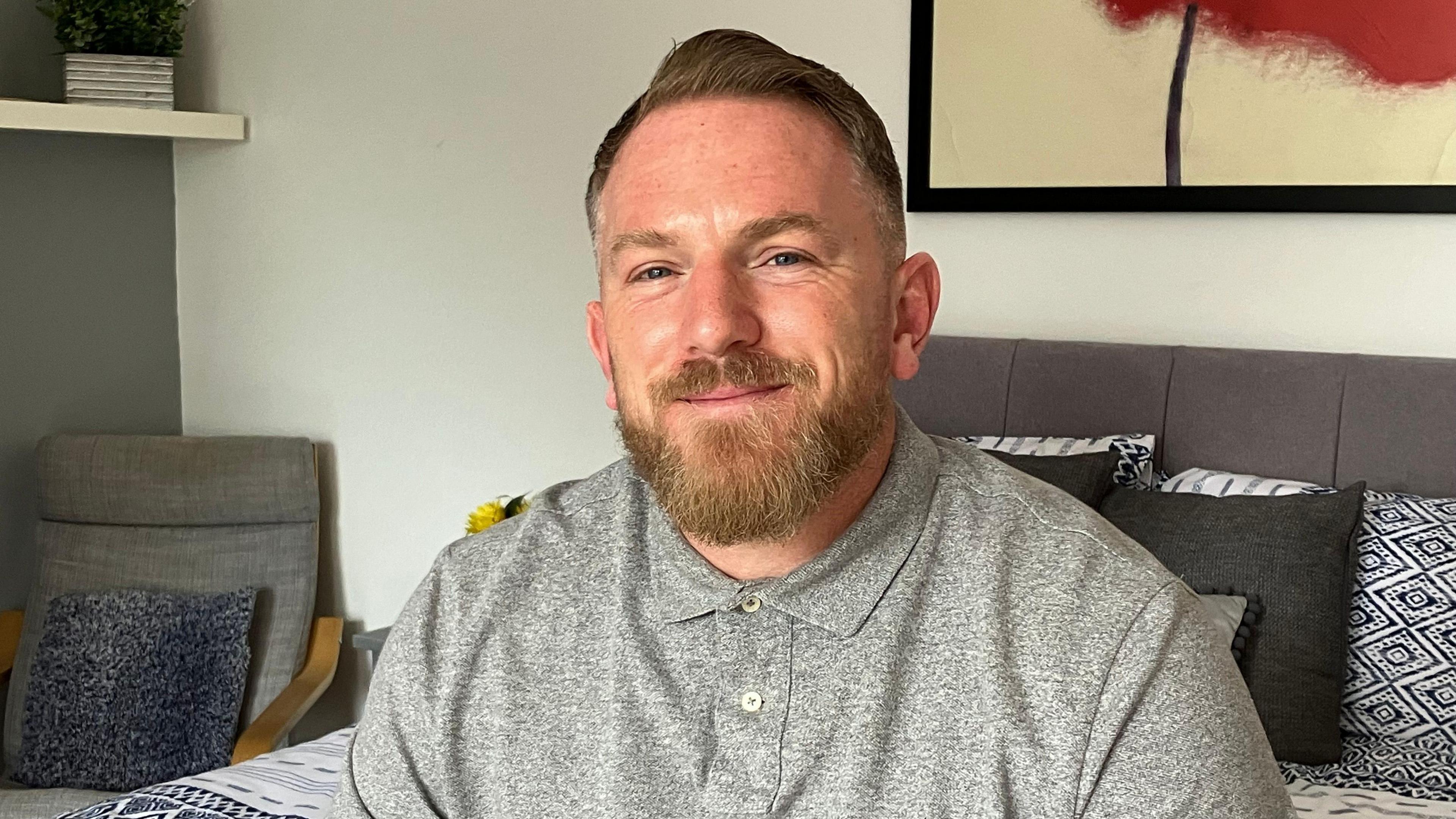 A man with a beard sitting on bed in new accommodation block of the charity's Harmony House