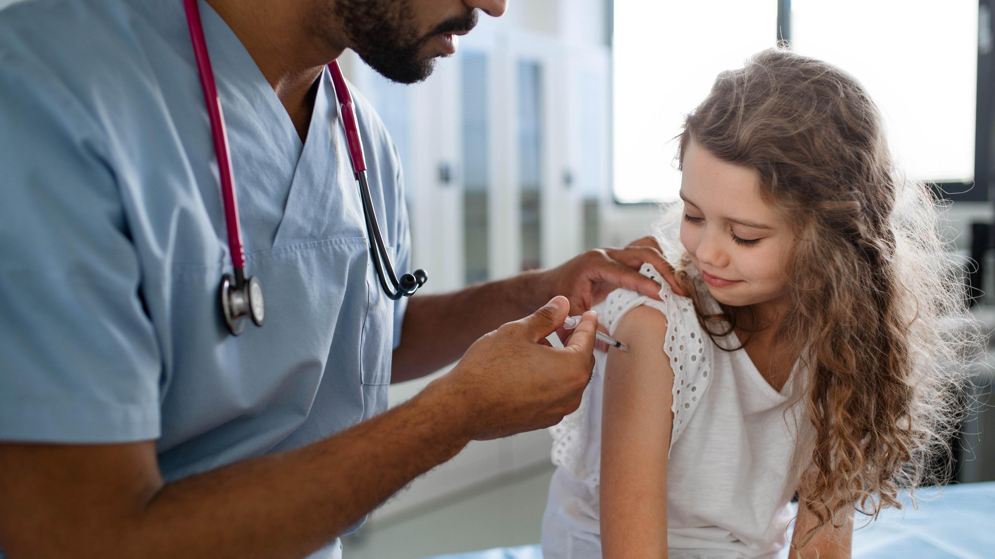 A doctor vaccinating a young girl.