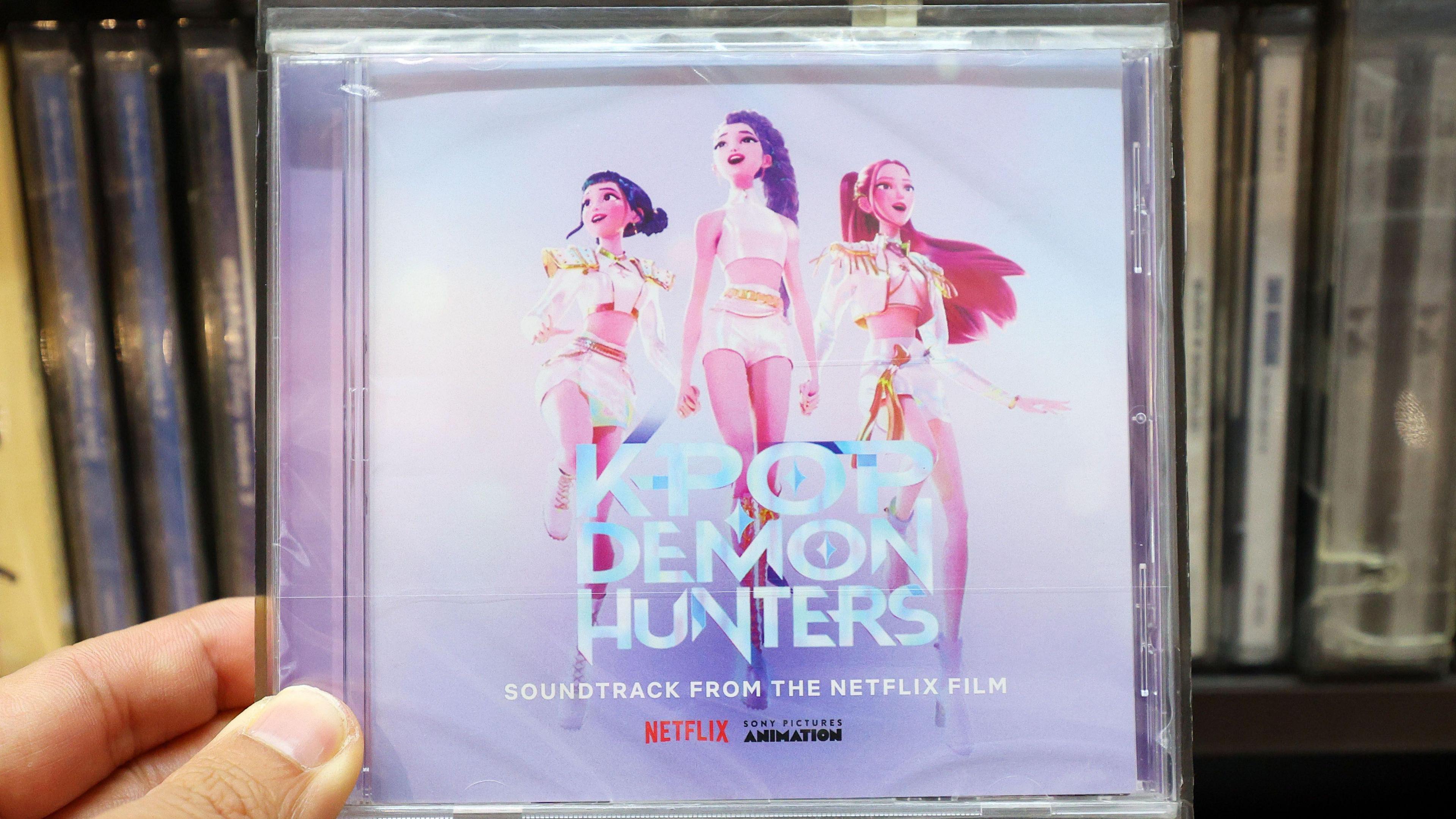 Image shows a hand holding a CD copy of the K-Pop Demon Hunters soundtrack album