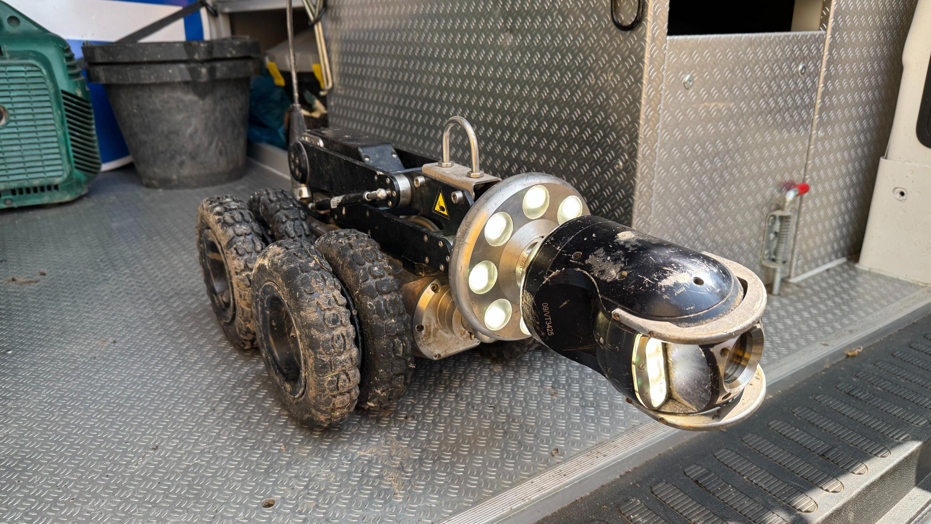 An eight wheeled robot which has a camera on the front and lights. the camera can be moved up and down. the robot goes up and down sewage pipes to inspect them.
