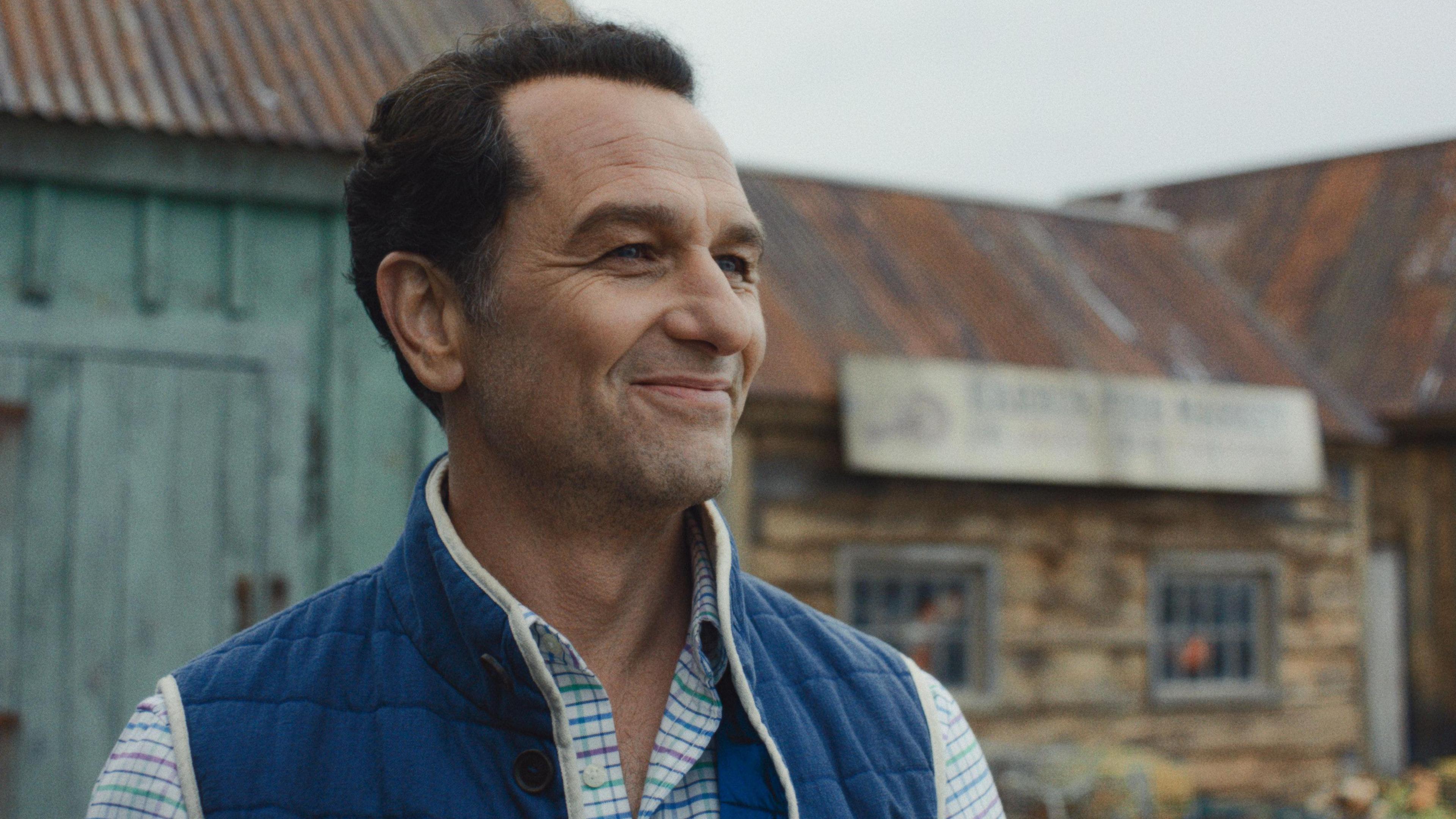 Matthew Rhys in a striped shirt and blue body warmer in a still from Widow's Bay