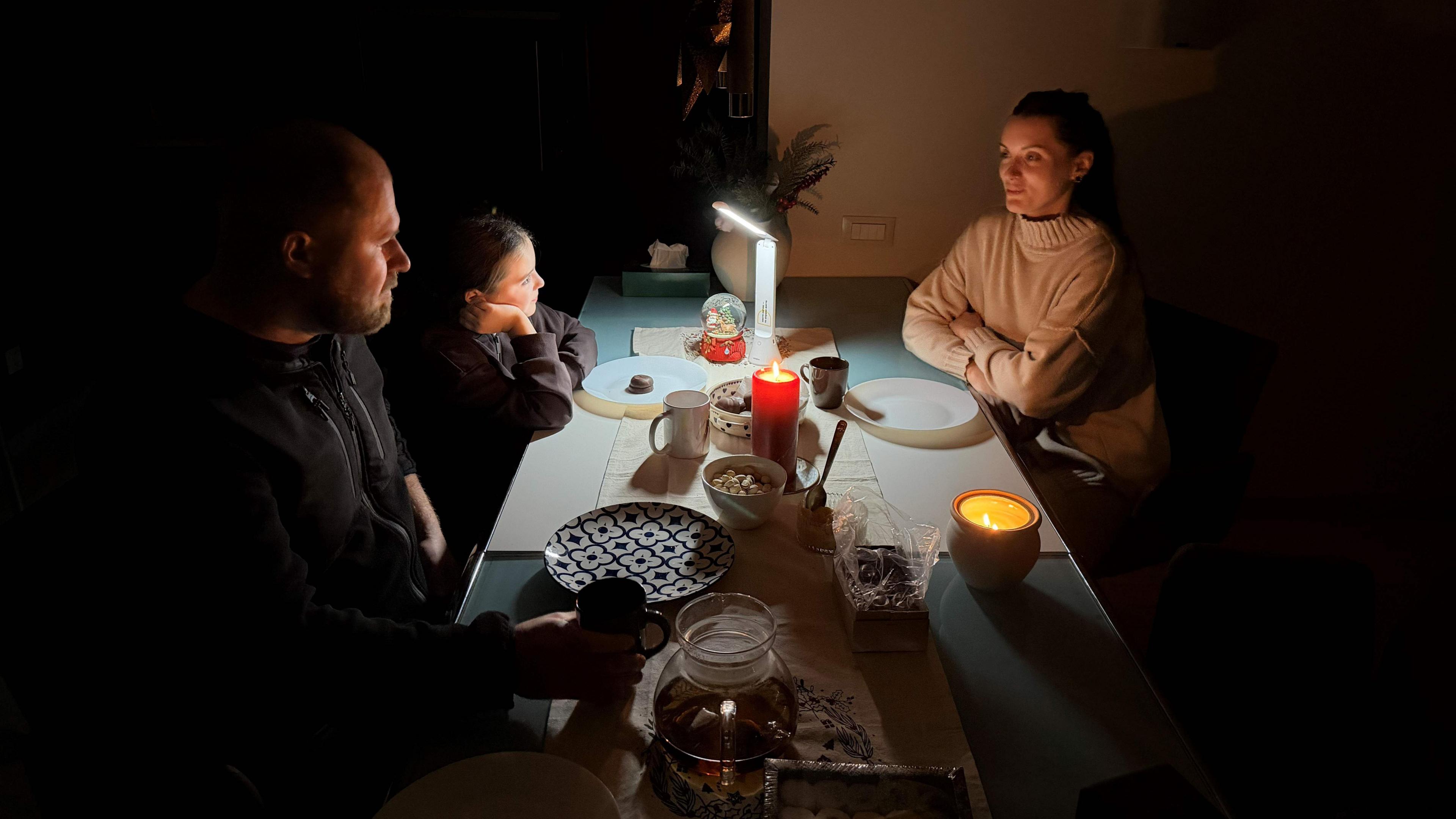 Një familje ulet rreth një tavoline në errësirë