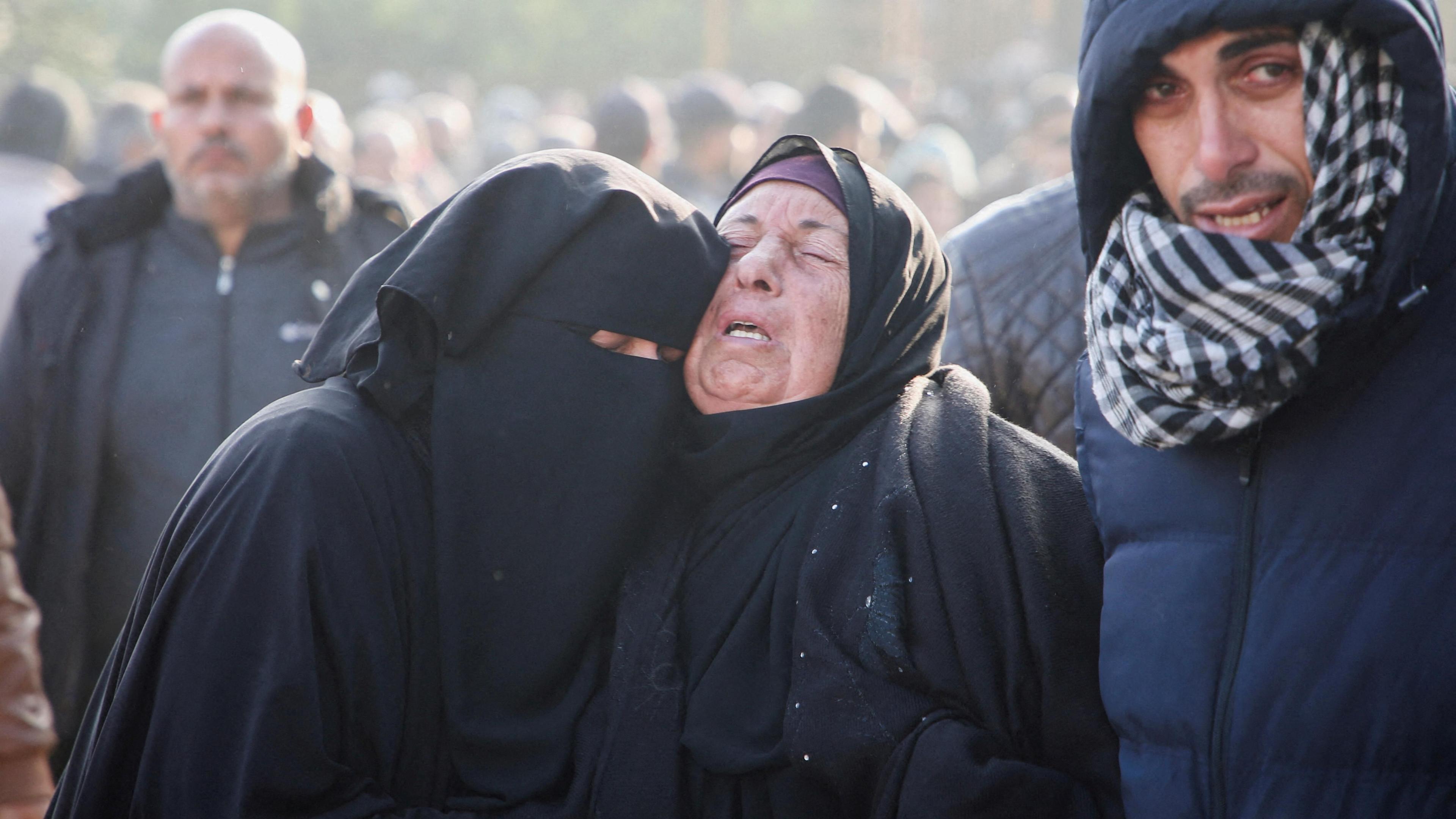 Two grieving women embrace near the bodies of Palestinians killed in Israeli air strikes, outside Nasser hospital, in Khan Younis, southern Gaza. Two men are seen either side of them and more people are in the background