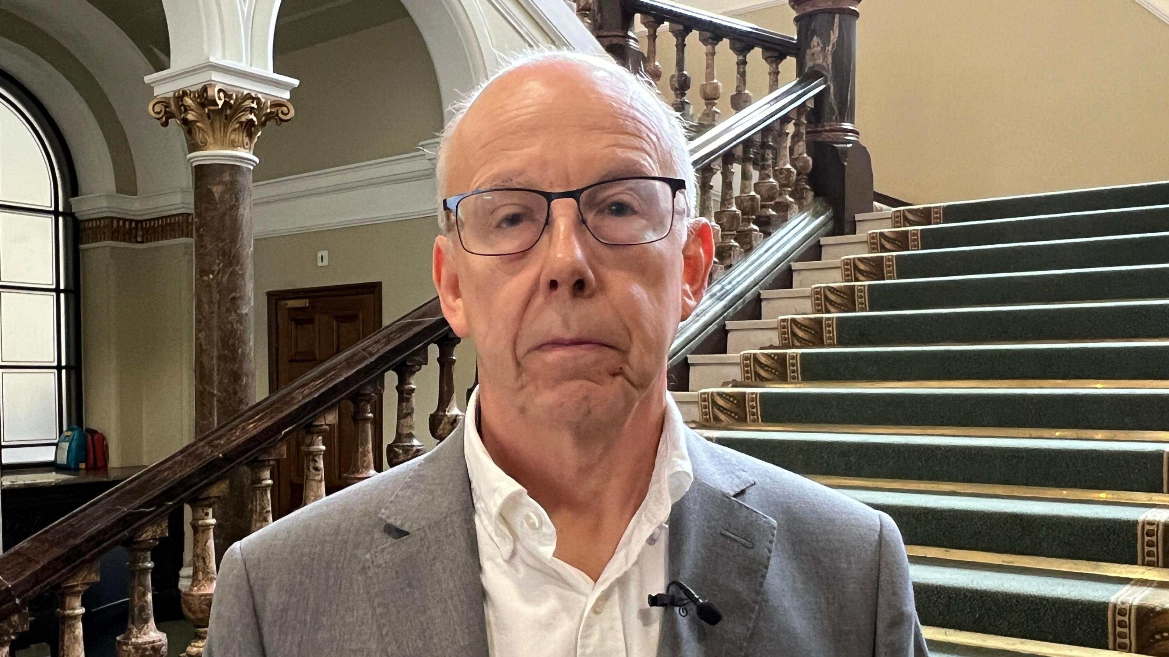 Image showing Councillor Meirion Jenkins, Conservative Shadow Cabinet Member for Finance at the council in front of a green carpeted staircase in Birmingham Council house.