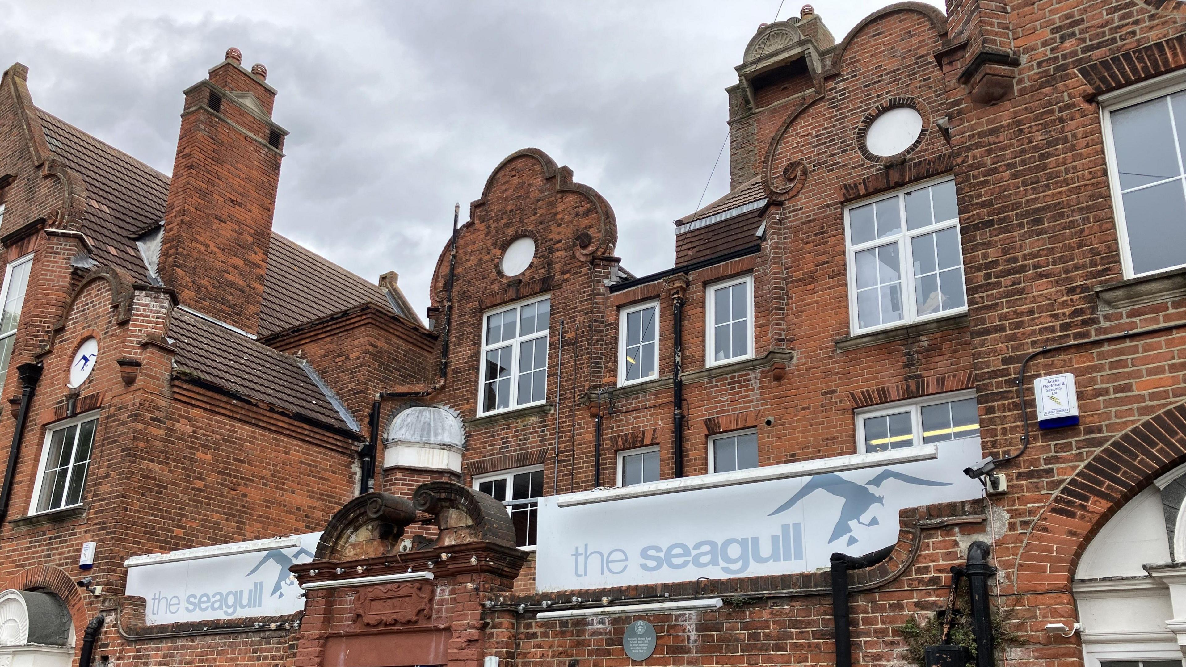 Red brick facade of theatre with tall chimney and large windows