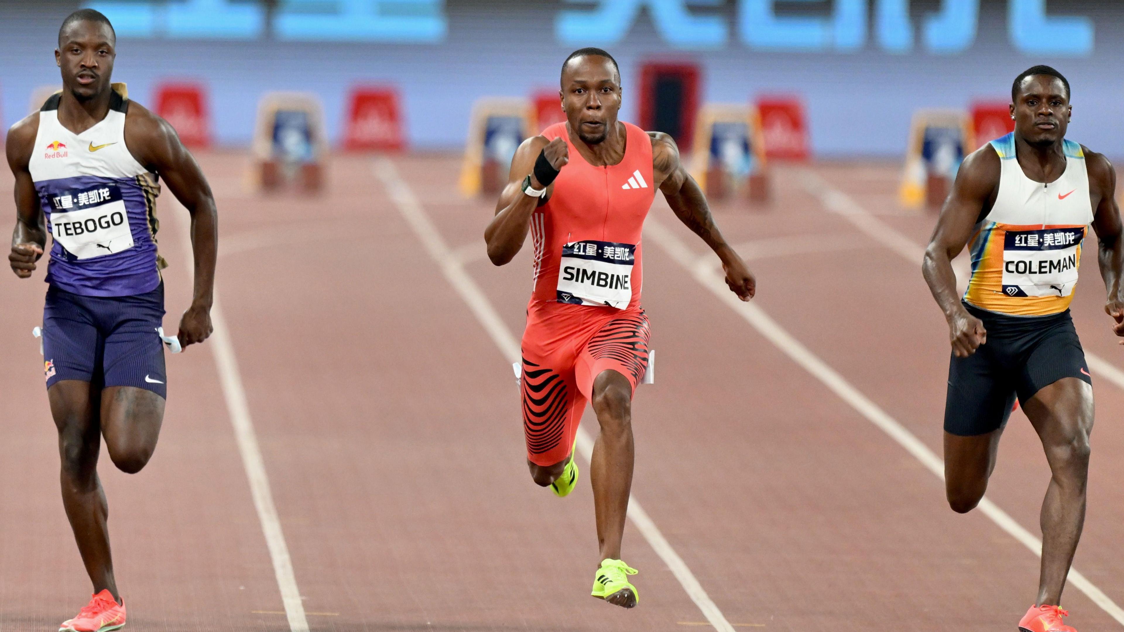 South Africa's Akani Simbine in red running gear flanked by USA's Christian Coleman and Botswana's Letsile Tebogo competes in the men's 100m final during the 2025 Xiamen Diamond League at Egret Stadium