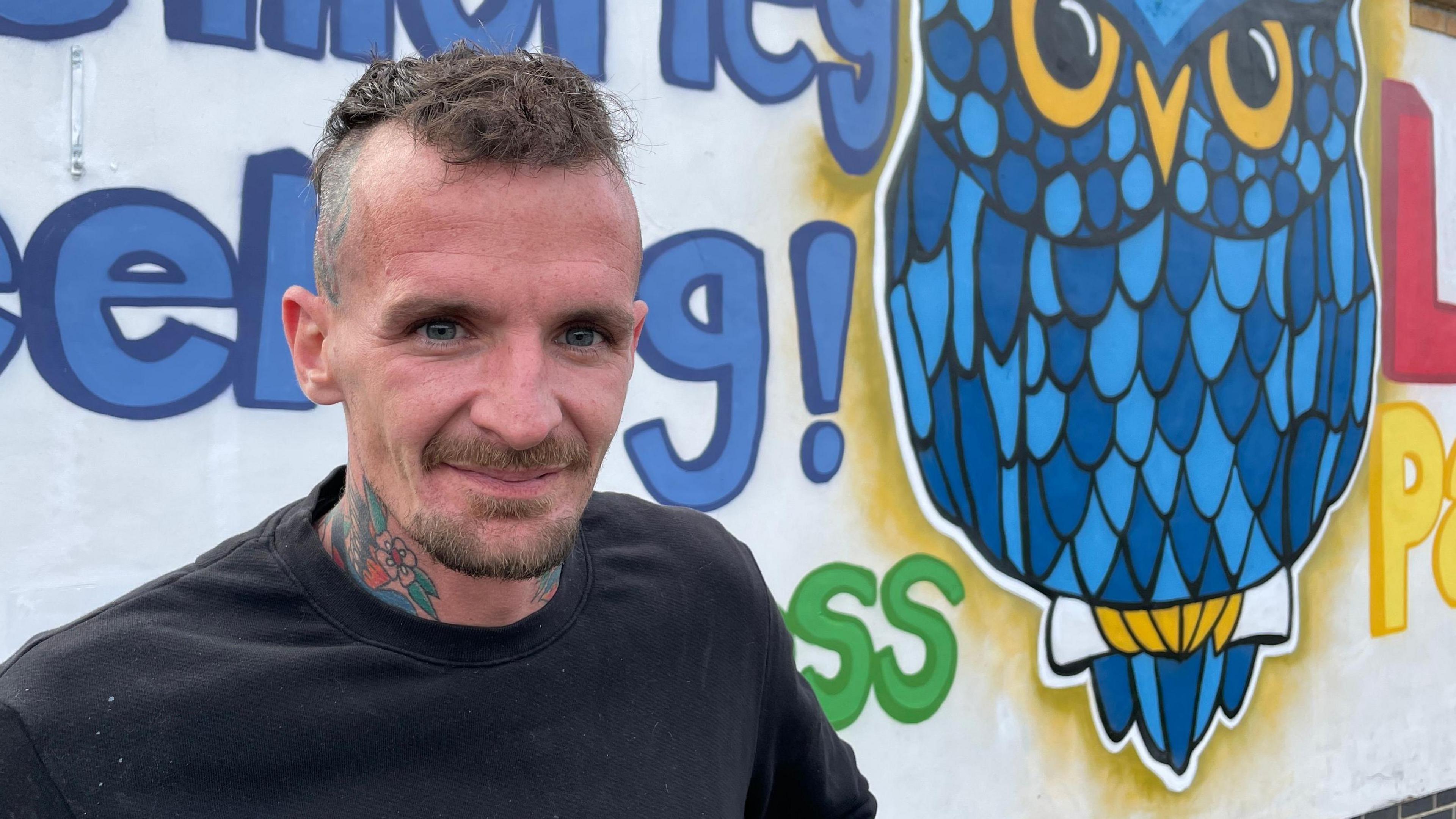 Darrell Wynne standing in front of his school art 