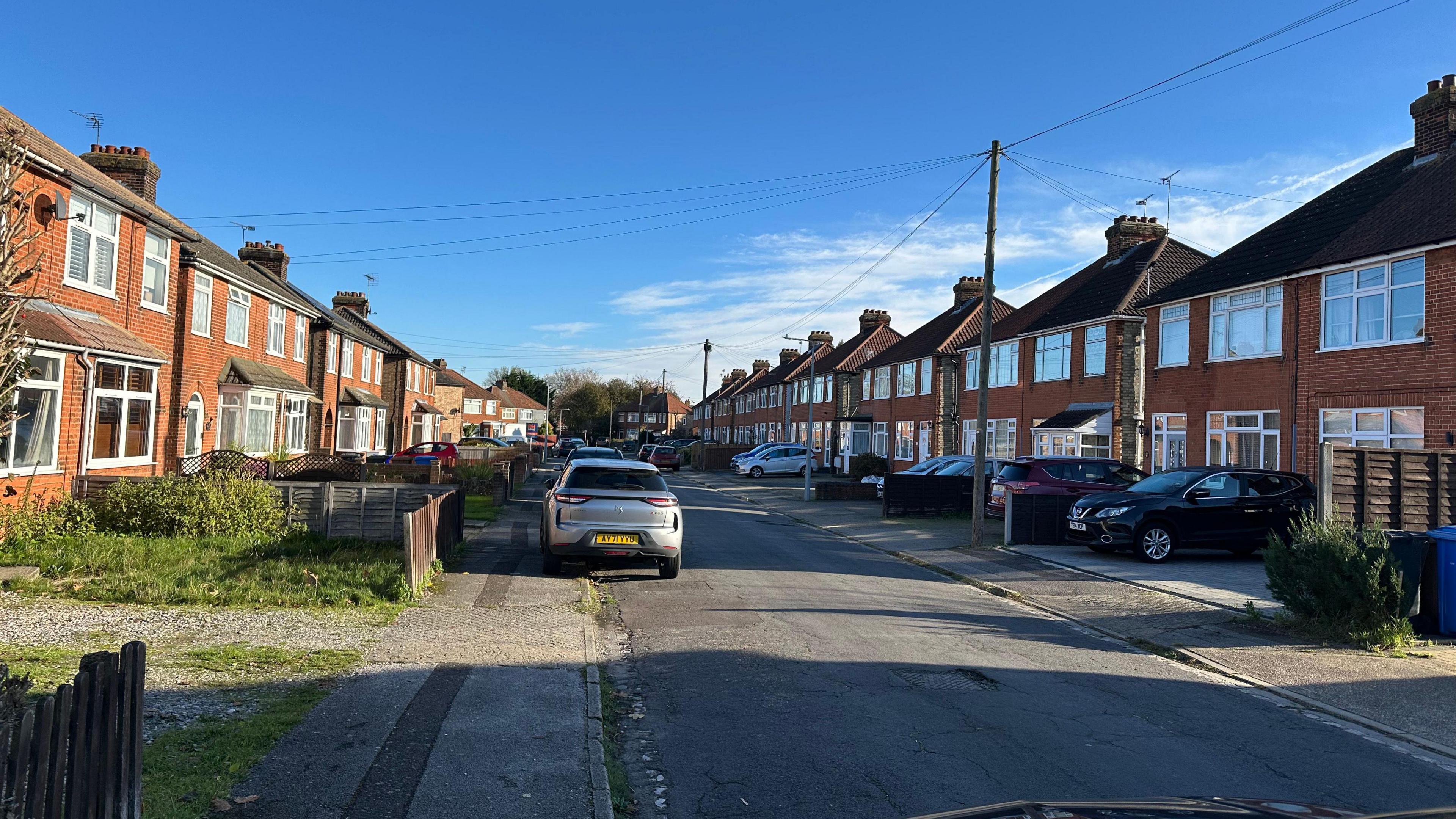 A wide view of Clarence Road in Ipswich showing detached houses on either side of the road and parked cars