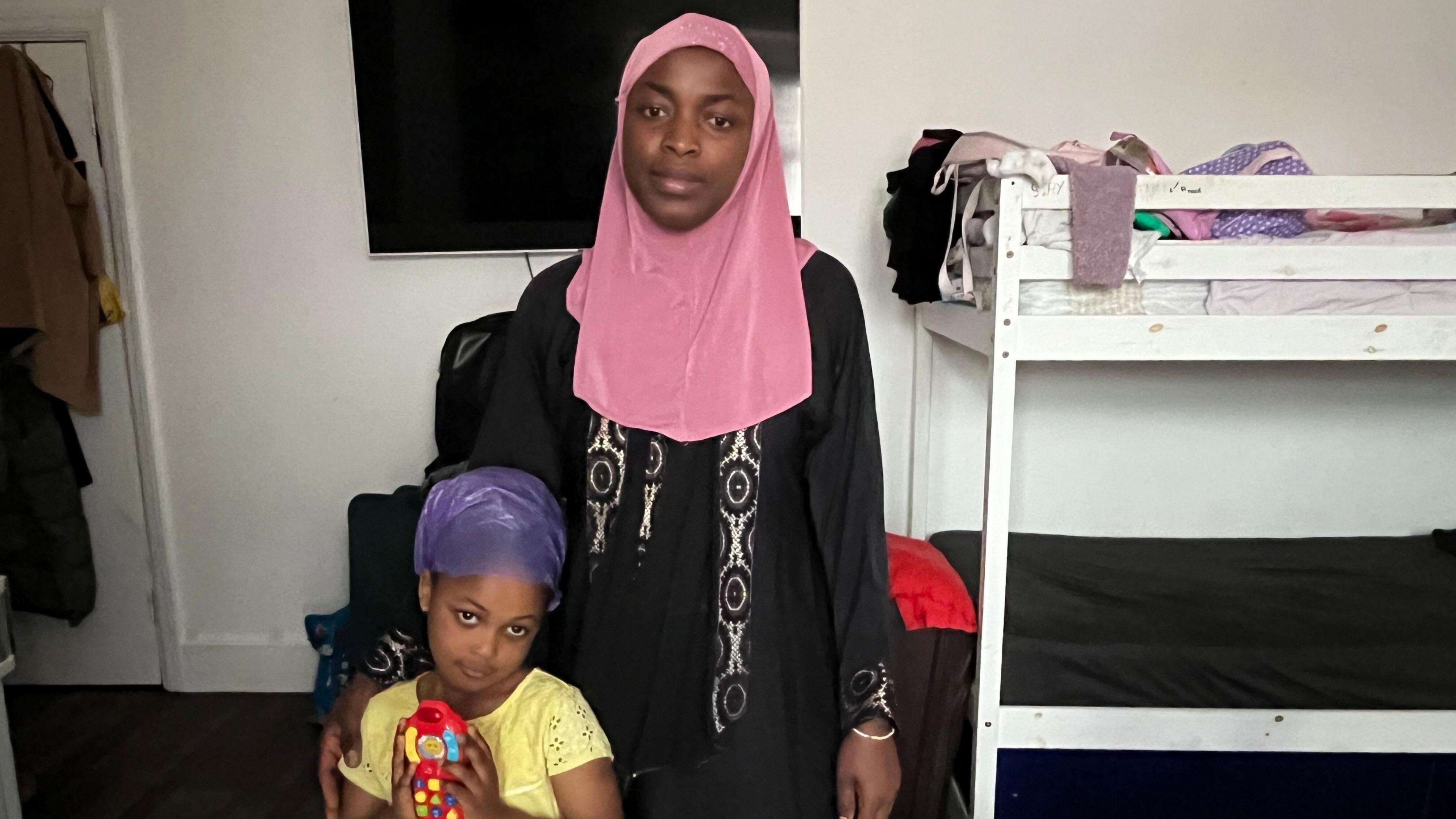 Five-year-old Habibah and her mum Jamaanu standing in their temporary accommodation