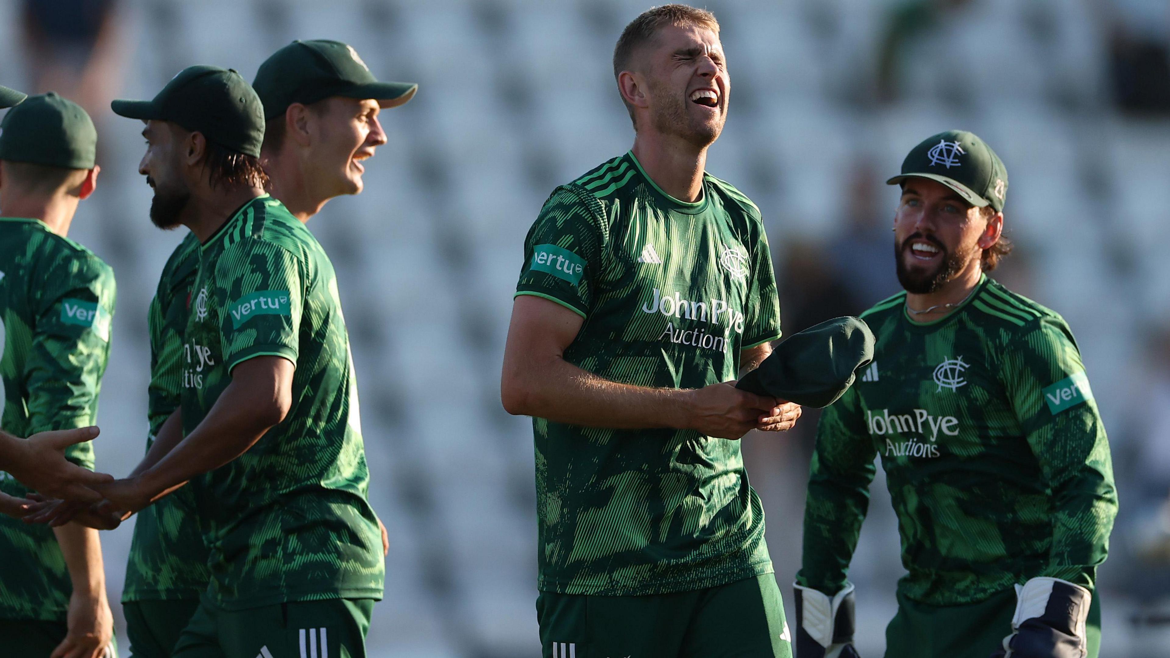 Olly Stone, wearing Notts Outlaws' green shirt, celebrates with his team-mates after beating Surrey.