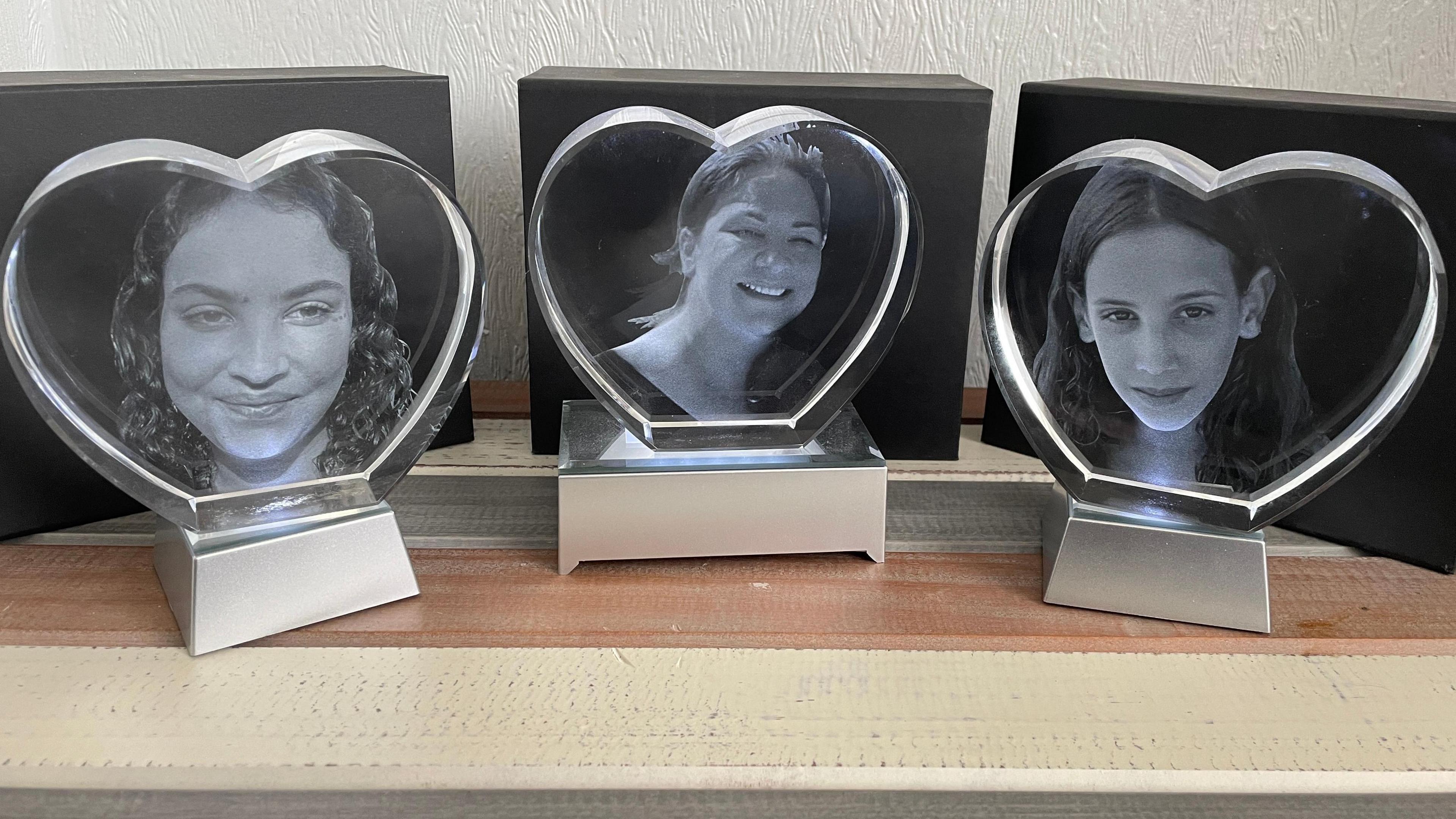 The black and white photographs of three women are displayed in three separate photo frames on a mantle piece. The first shows a teenage girl with dark curly hair, the second shows an older woman with her hair in a pony tail and the third shows a girl with long, straight hair. 