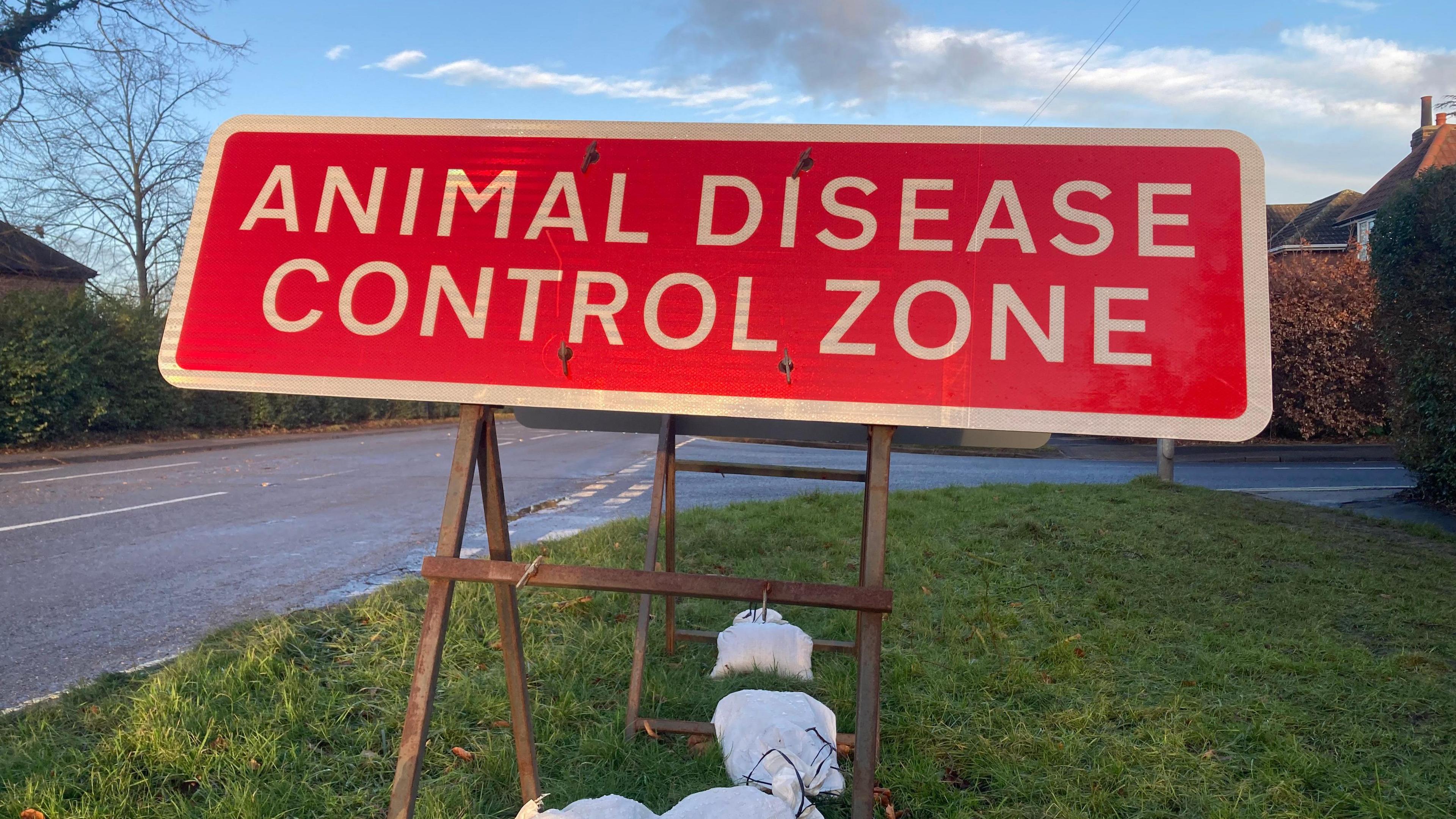 A red sign on the side of a residential road reading "animal disease control zone".