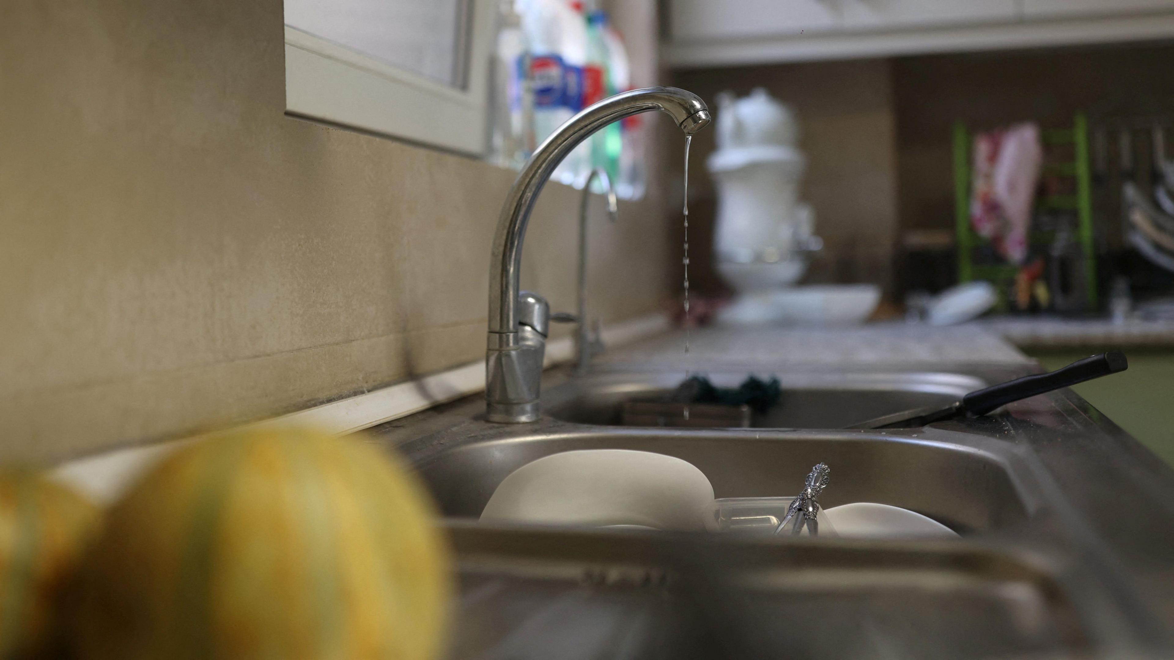 A small amount of water pours out of the tap in a kitchen