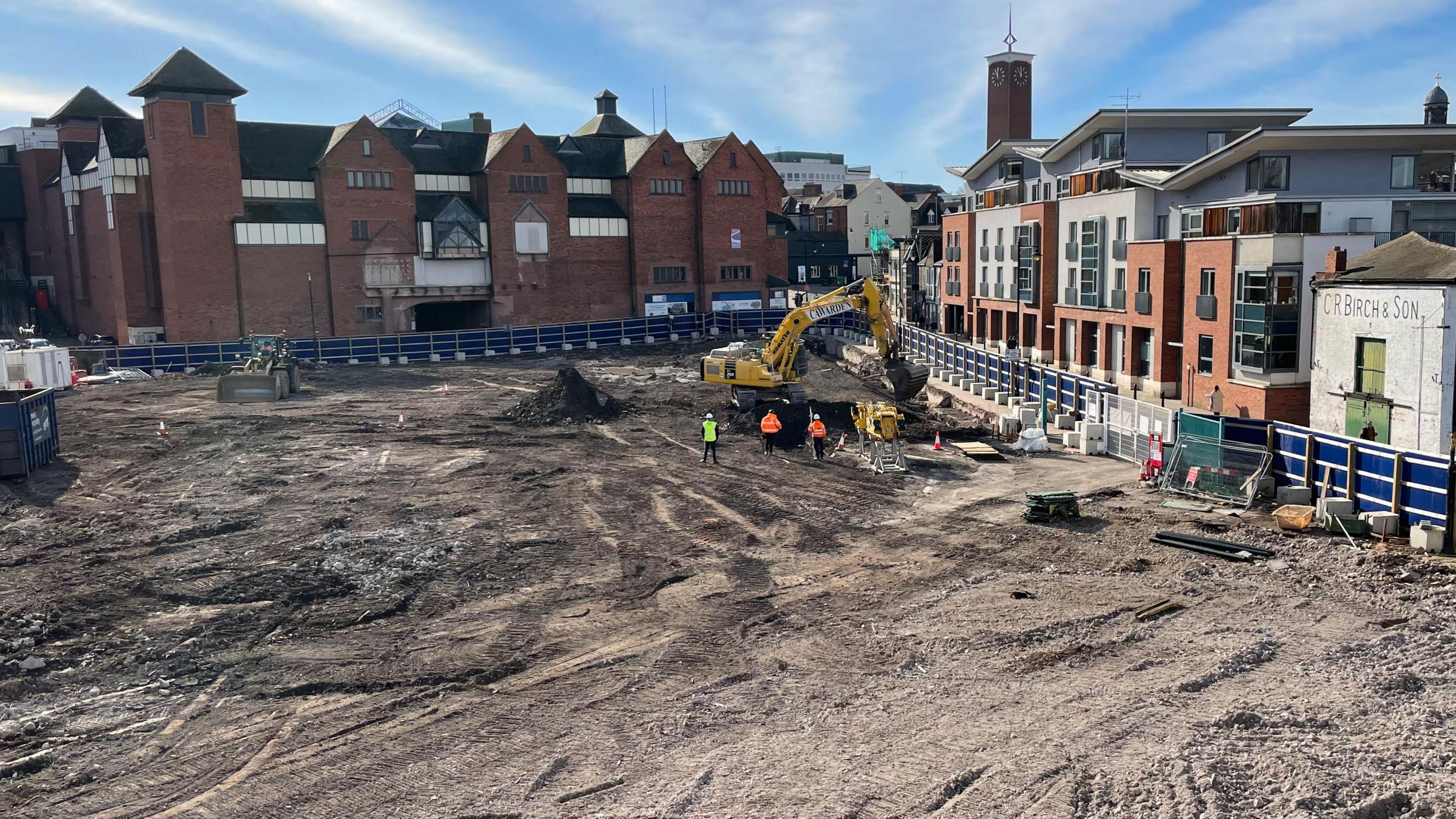 A digger is being used to work on the construction site where the park will be created after buildings were demolished. Shrewsbury's buildings can be seen behind the site.