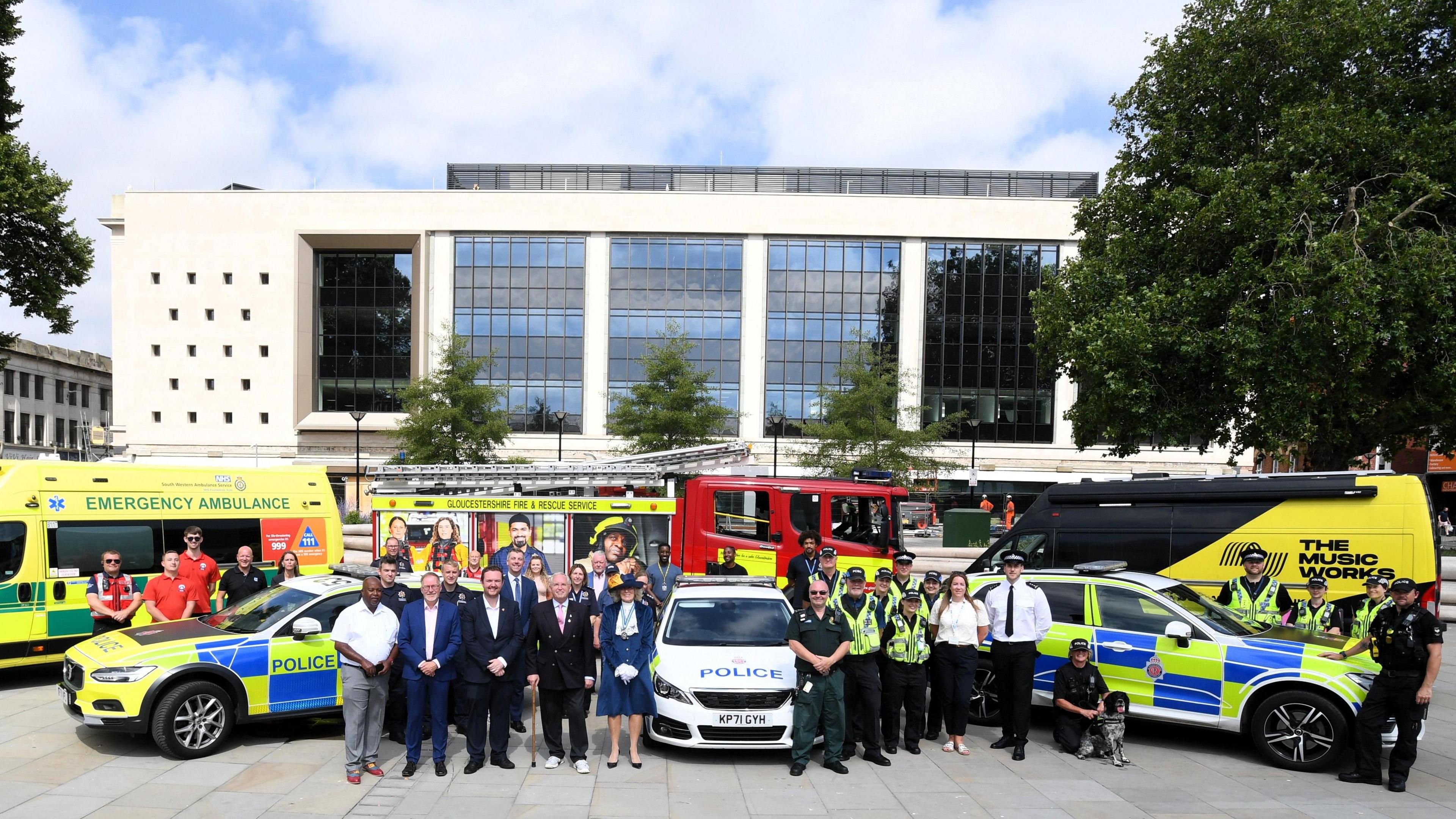 A group of people at Kings Square surrounded by ambulances, fire engines and police cars.