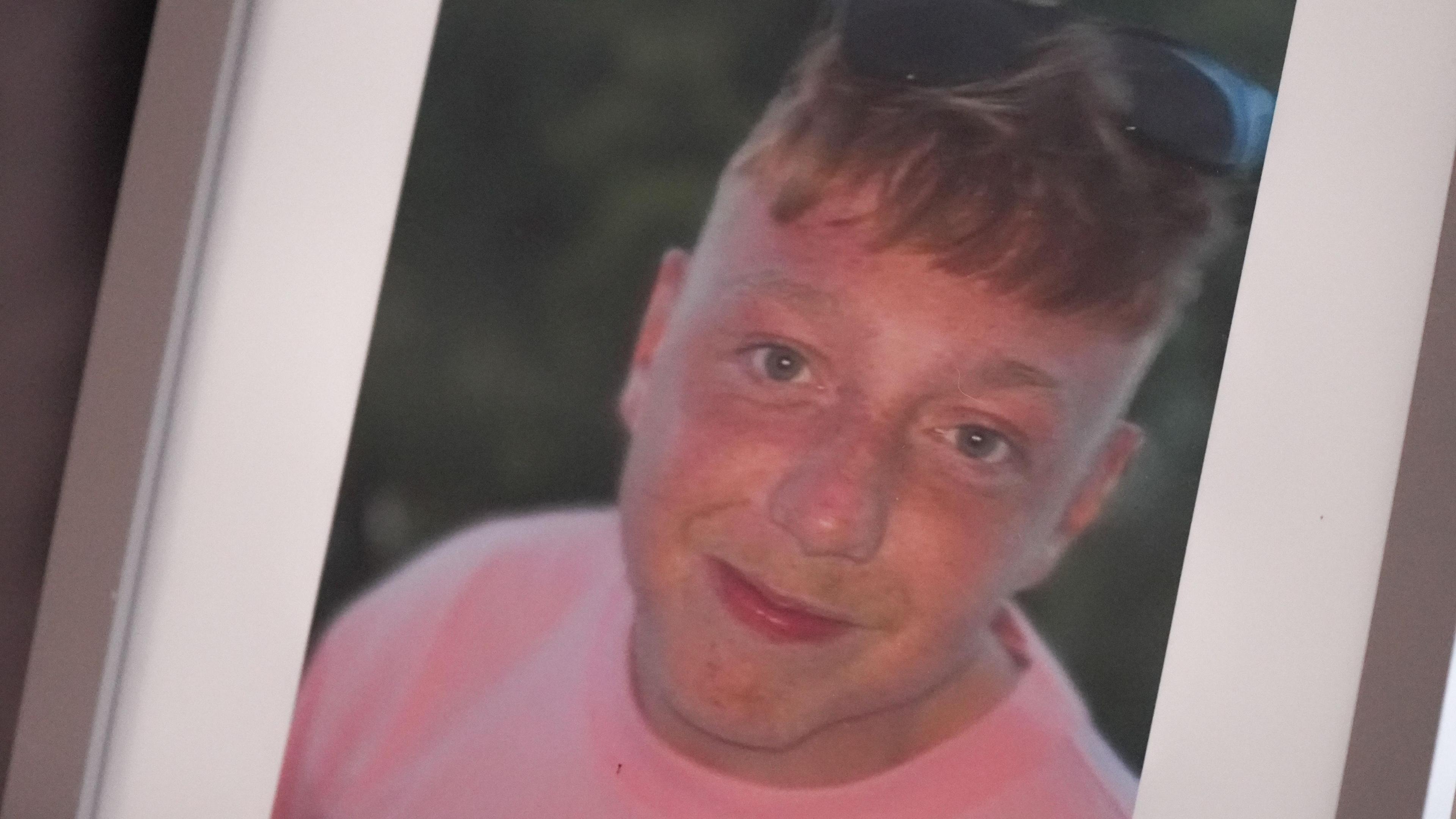 A photo of Callum Griffiths smiling, wearing a pink tshirt.