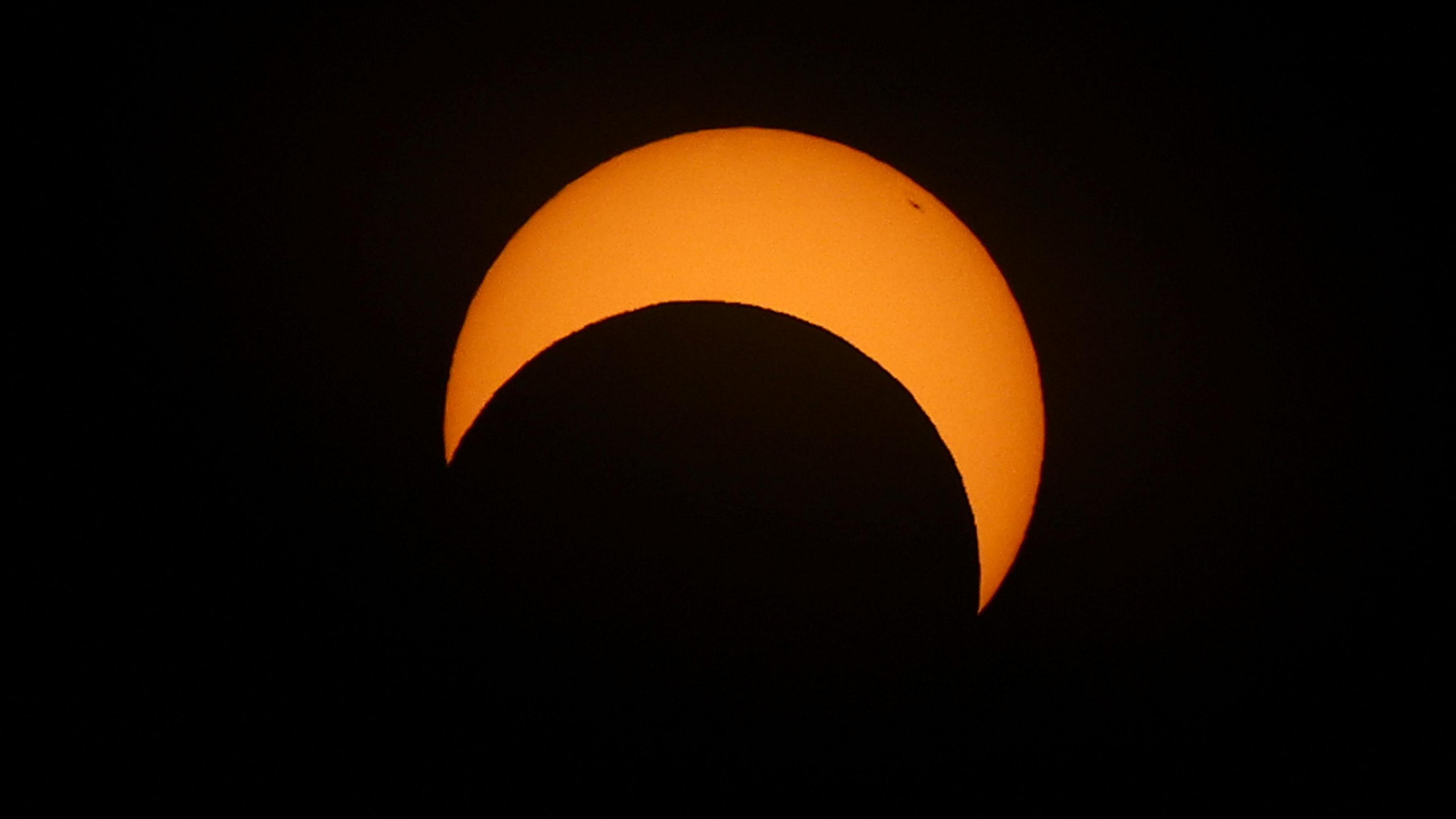 The moon passes the sun during an annular solar eclipse, in Las Horquetas, Santa Cruz, Argentina. The orange sun looks like a "C" on its side as the moon passes it.