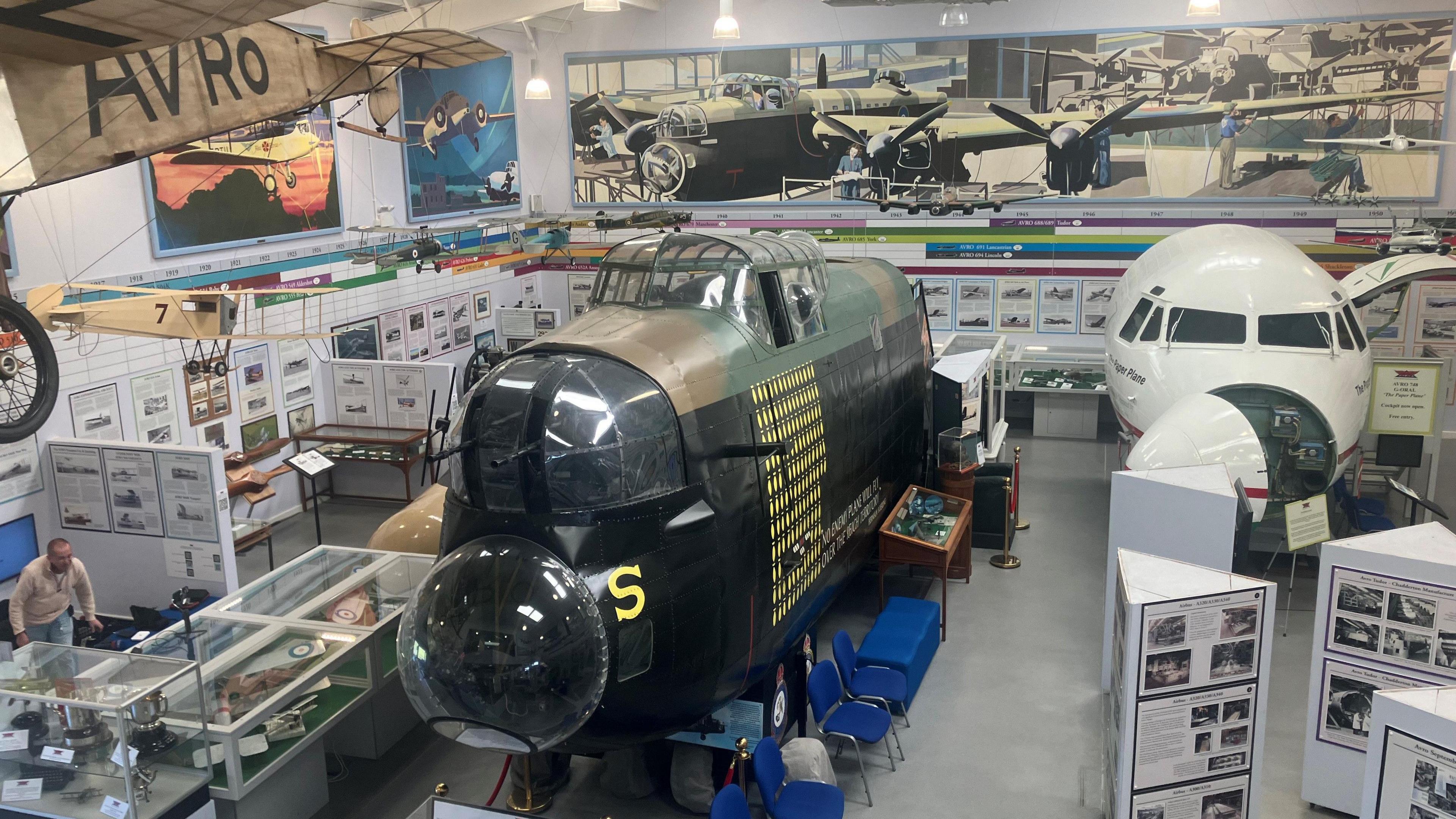 The nose cone of a World War 2 bomber and other planes alongside display cases at the museum at Woodford Aerodrome in Stockport