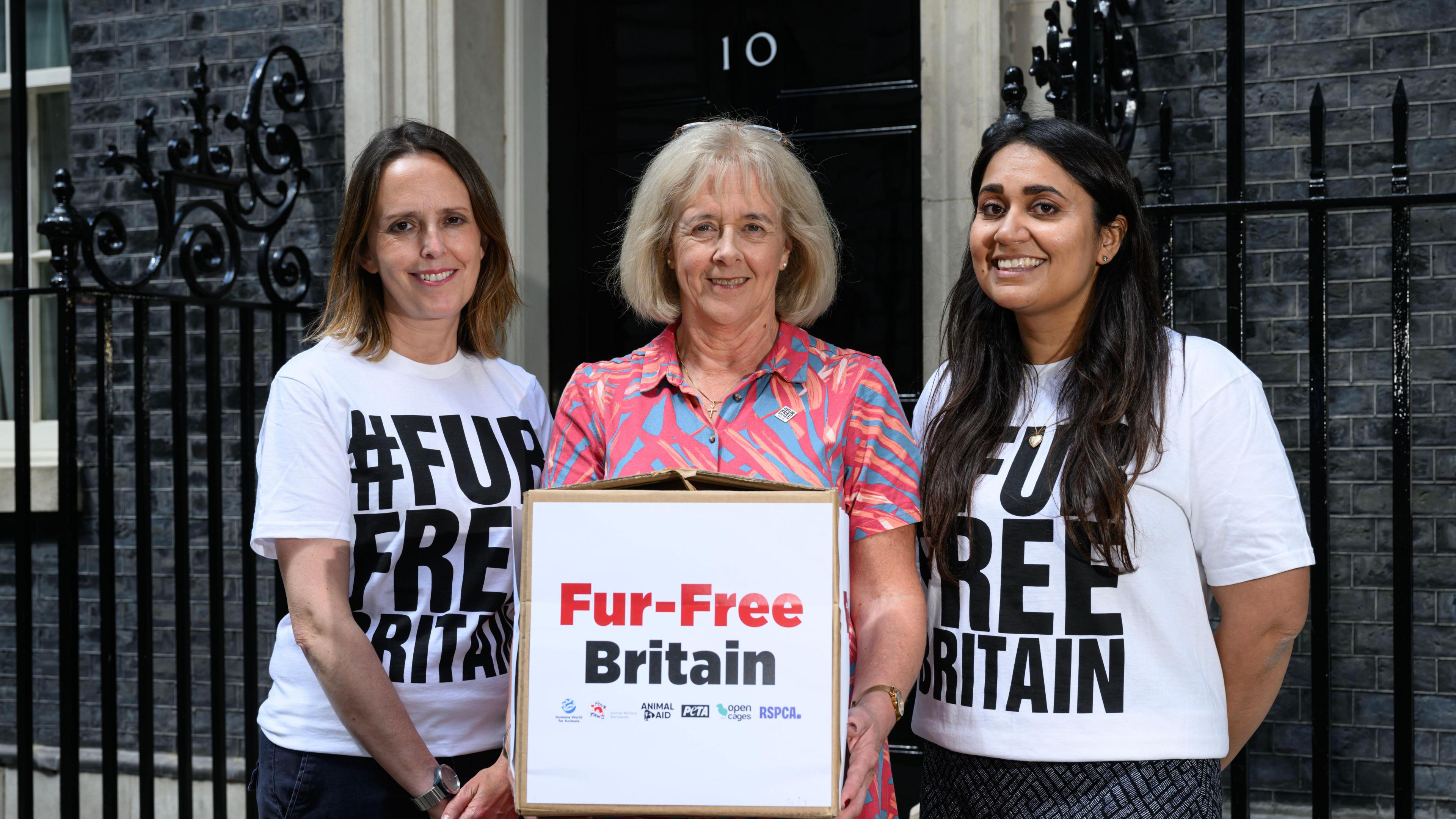 Y tu allan i rif 10 Stryd Downing mae Ruth Jones yn sefyll rhwng dwy fenyw sy'n gwisgo crysau-t gwyn gyda'r geiriau '#FUR FREE BRITAIN' arnyn nhw. Mae Ruth Jones yn y canol yn dal bocs gyda'r testun yno arno hefyd.
