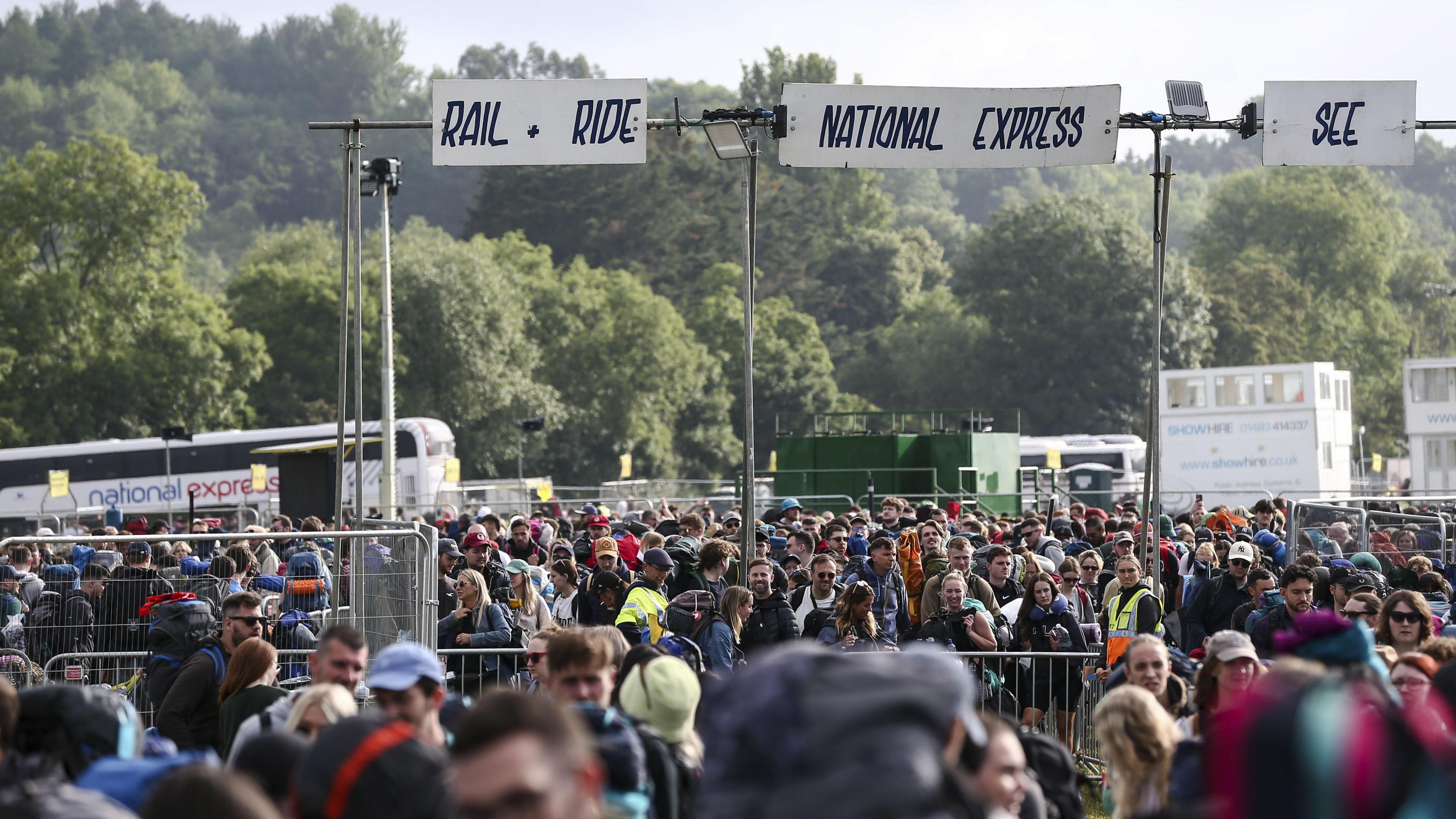 Image of gates at Glastonbury. Large crowds of people can be seen by gantries for National Express and railways.