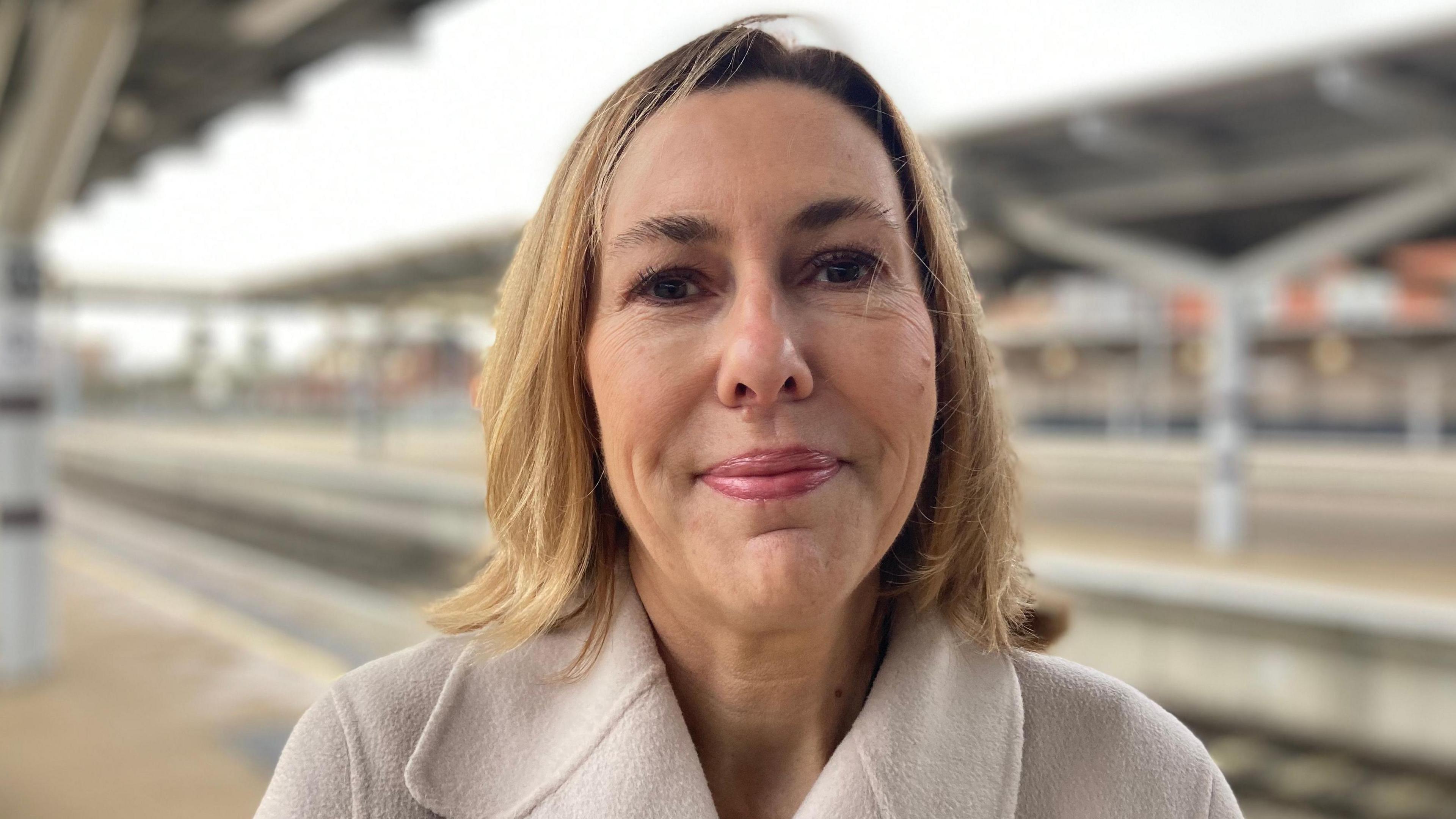 A woman with blond hair, brown eyes and wearing a white jacket